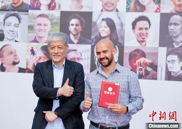 图为深圳报业集团社委会委员、编辑委员会副总编辑胡洪侠(左)为自然组一等奖获得者(哥伦比亚)颁奖点赞。陈文 摄