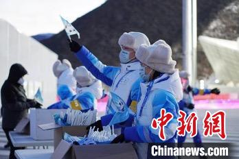 图为志愿者向观众发放冰墩墩旗帜。　北京冬奥组委供图
