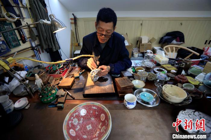王培波手里拿着金刚钻对瓷器进行打孔。　王磊 摄