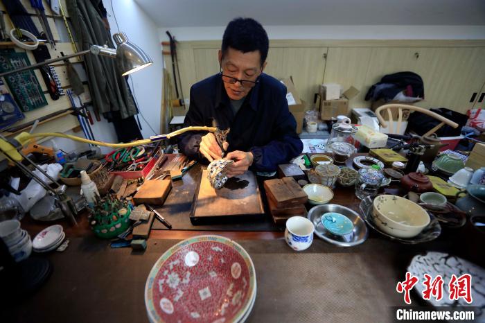 王培波手里拿着金刚钻对瓷器进行打孔。王磊 摄