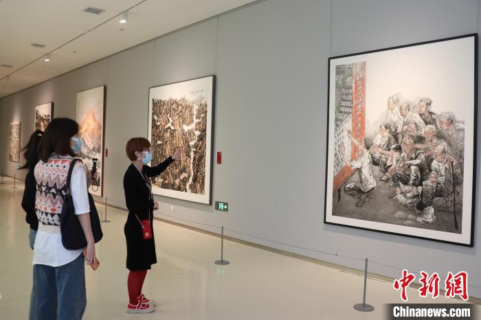 工作人员向参观者介绍美术作品背后的故事。李明芮 摄