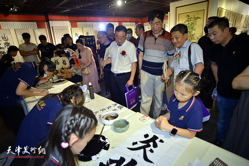 姜维群、方大开、赵光观赏桐林书院的小画家们写字作画。