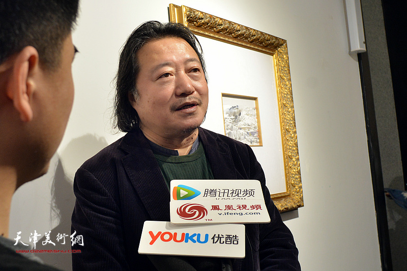 纪连彬在画展现场接受媒体采访。