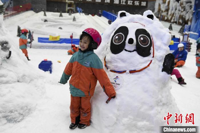 一位小朋友与雪雕冰墩墩合影。　杨华峰 摄
