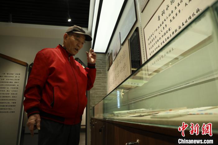 郭华老人正在讲解村使馆内陈列物品背后的故事。 向上 摄