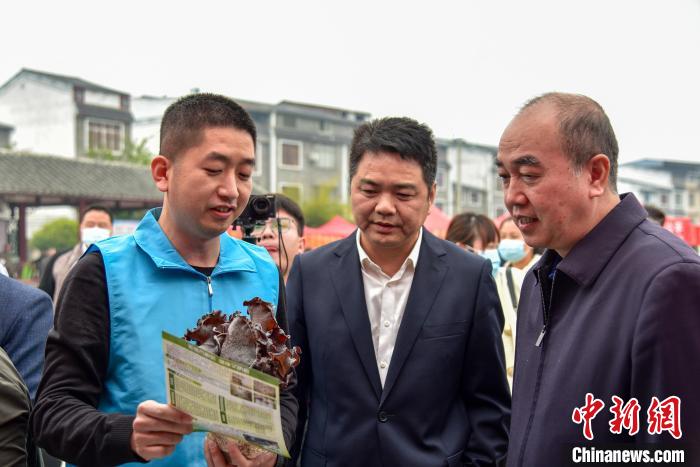 洪龙金(左)向嘉宾介绍食用菌产业的发展。　王以照 摄