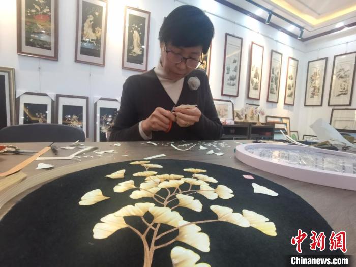 麦秆画制作技艺市级非遗传承人孙秀英，是张掖民乐县人。图为她在工作室裁剪熨好的麦秆。　闫姣 摄